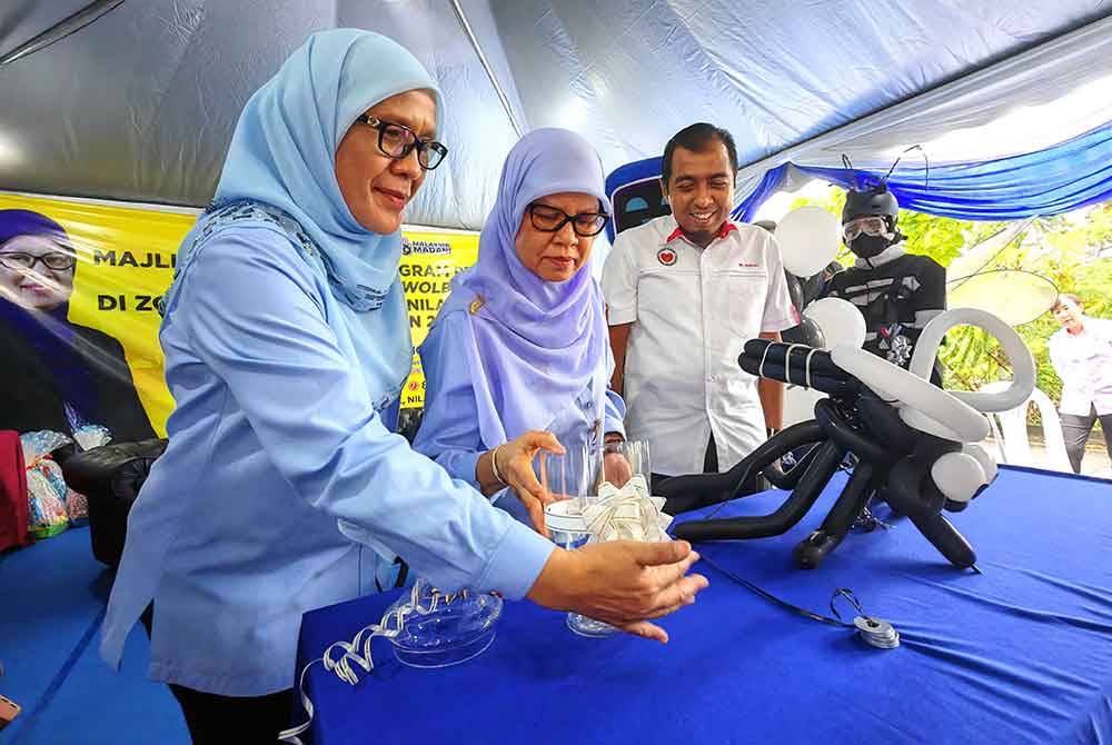 Zamrah (tengah) melepaskan nyamuk aedes berwolbachia sambil dibantu Harlina pada Pelancaran Program Pelepasan Nyamuk Aedes Berwolbachia peringkat Negeri Sembilan.