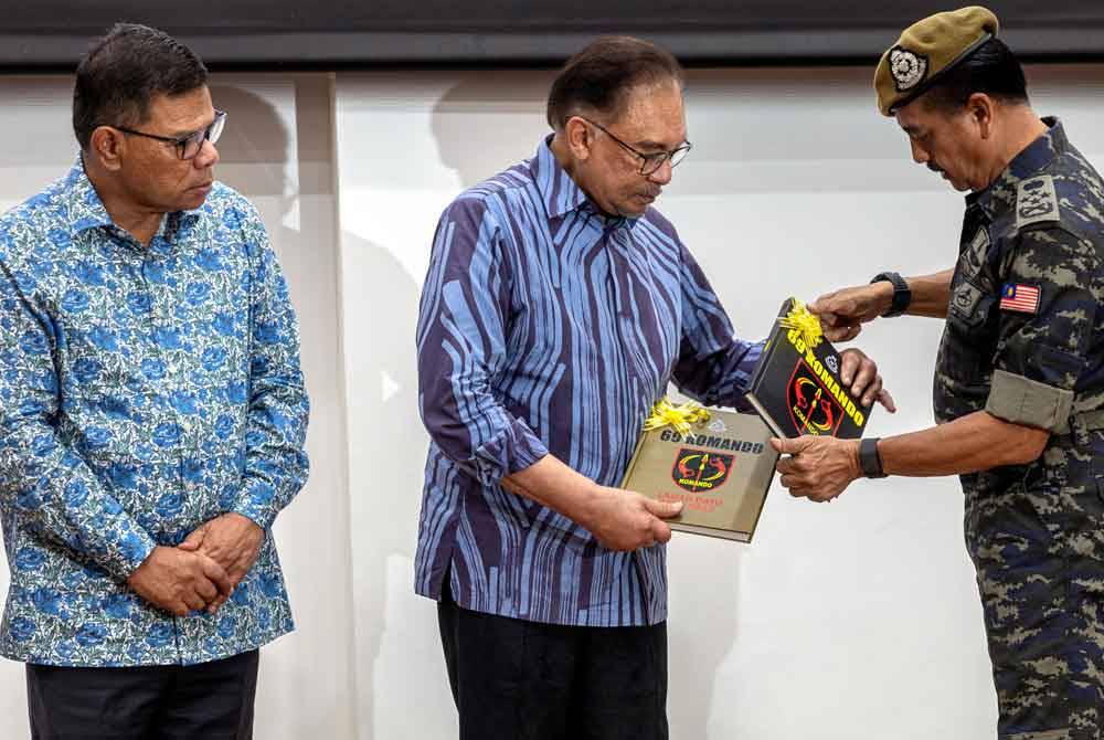 Anwar (tengah) menerima buku 69 Komando dari Razarudin (kanan) pada Majlis Ramah Mesra Raya Madani bersama Warga Unit 69 Komando, Pasukan Gerak Khas, Ulu Kinta di Pusat Latihan Unit 69 Komando pada Sabtu. Turut hadir, Saifuddin Nasution. Foto Bernama