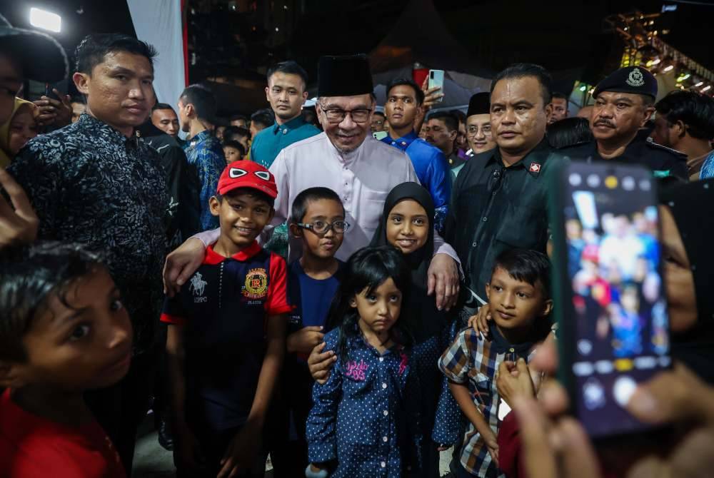 Anwar menyantuni kanak-kanak pada Rumah Terbuka Aidilfitri anjuran Persatuan Khalifah Jelutong, malam Sabtu. Foto Bernama