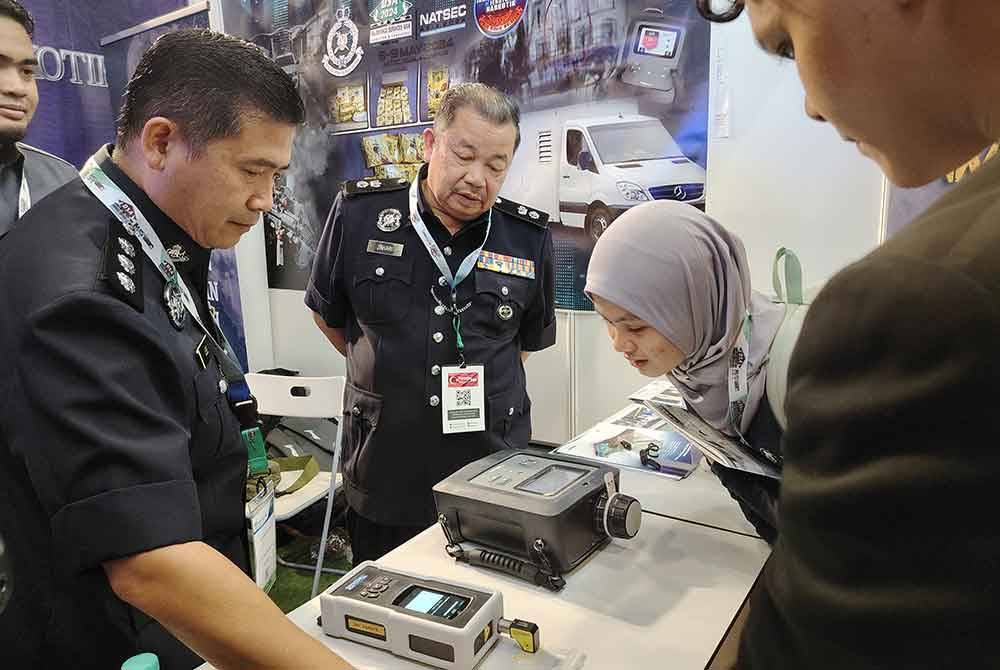 Zahari (kiri) berkongsi kepada pengunjung cara peralatan pengesanan dadah berfungsi.