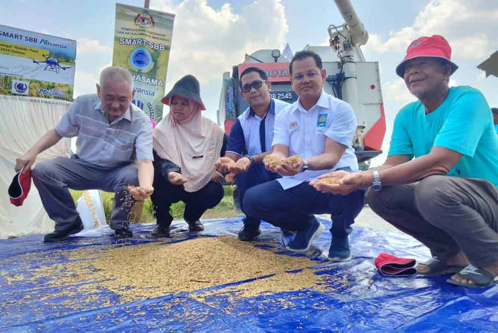 Azman (dua dari kanan) menunjukkan hasil padi pada Majlis Dialog dan Perasmian Penuaian Padi Sempena Program Smart Sawah Berskala Besar (Smart SBB) IADA Kemasin, Semerak pada Selasa.