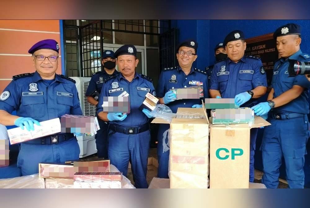 Ribuan (kiri) dan Mohd Asri (dua dari kiri) bersama pegawai JKDM Pahang menunjukkan sebahagian rokok seludup yang dirampas dalam dua serbuan di Johor, pada April lalu.