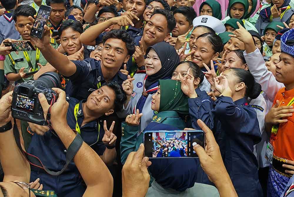 Fadlina (tengah) me layan permintaan pelajar - pelajar untuk berswafoto dengannya