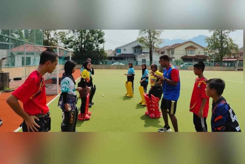 Kumar (tiga dari kanan) berkongsi ilmu sebagai penjaga gol kepada pelajar sekolah. Foto MHC