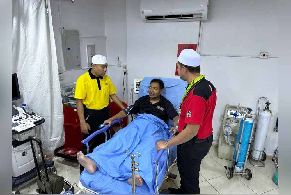 Shukri (kiri) membantu pakar perubatan kecemasan, Dr Reza Murad Qamruddin (kanan), dalam operasi harian Pusat Rawatan Madinah di Hotel Roha.