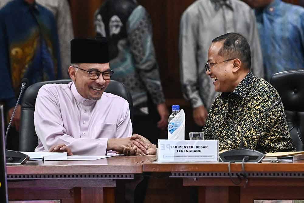 Anwar (kiri) beramah mesra dengan Ahmad Samsuri semasa menghadiri Mesyuarat Khas Pembangunan Negeri Terengganu di Wisma Darul Iman pada Khamis. Foto Bernama