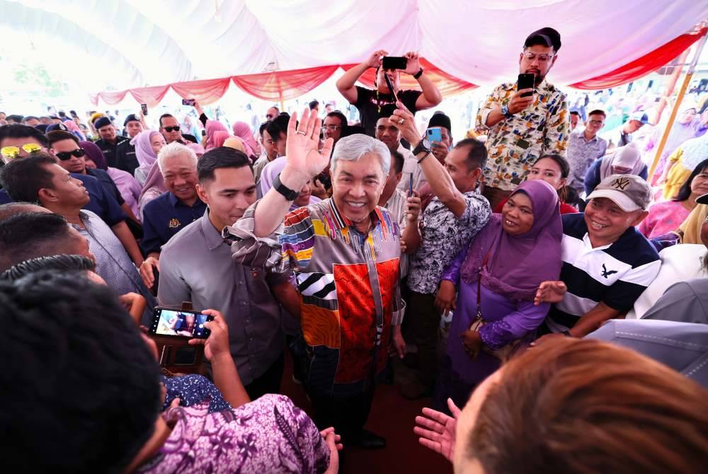 Ahmad Zahid (tengah) melambaikan tangan kepada orang ramai sewaktu tiba untuk merasmikan Sentuhan Kasih Desa KKDW dan Keusahawanan Desa Madani di Dataran Tamu, Sukau pada Khamis. Foto Bernama