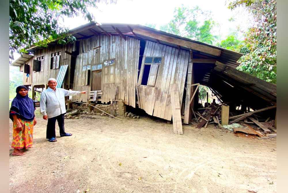 Din dan isteri menunjukkan rumah yang dihuni roboh, malah ada sebahagiannya telah dihanyutkan arus pada bah Disember lalu di Kampung Tersang di Rantau Panjang.