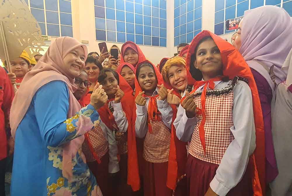 Fadhlina (kiri) bergambar bersama murid-murid pada Karnival HIP di Sekolah Menengah Kebangsaan Saujana Indah di sini, pada Jumaat.