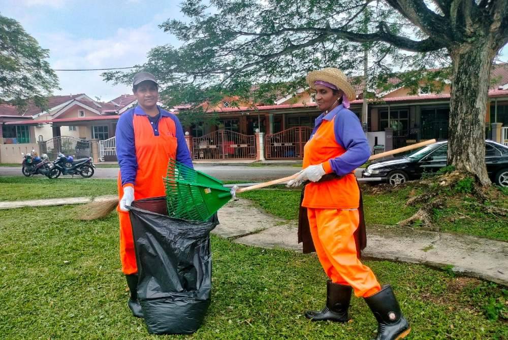 Selve (kiri) bersama rakan baiknya ketika menjalankan kerja-kerja pembersihan di Taman Meranti Lestari, Alor Gajah, Melaka.
