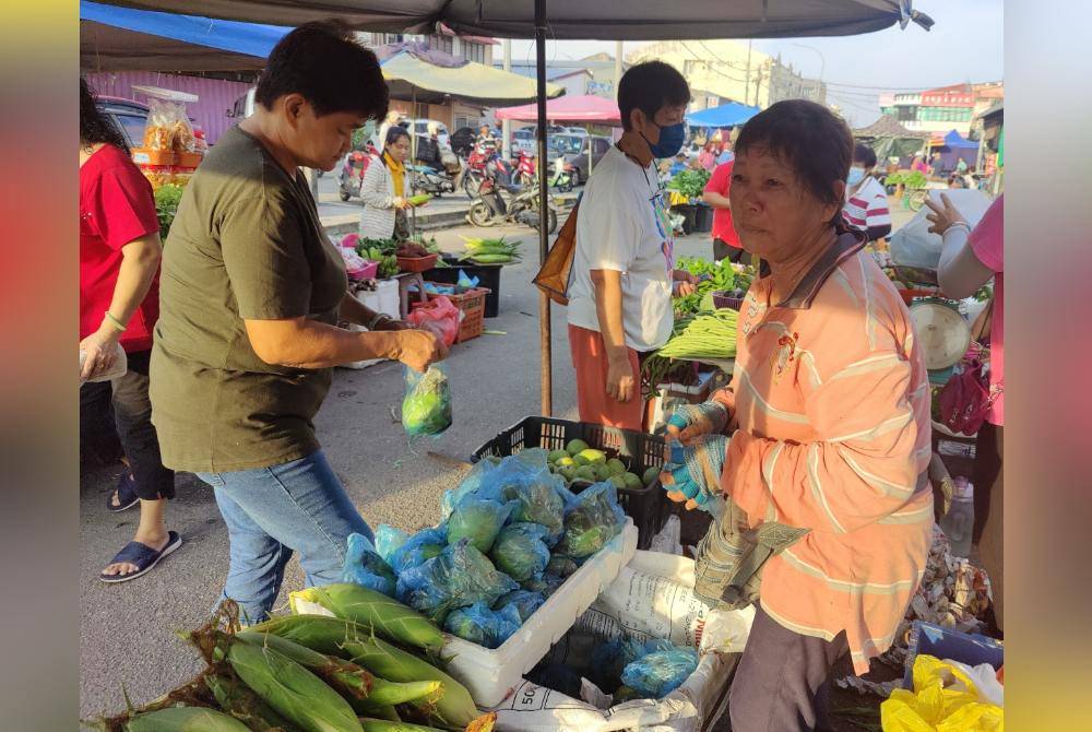 Git Ngo berniaga sayur-sayuran demi kelangsungan hidup di tapak pasar pagi di Sekinchan.