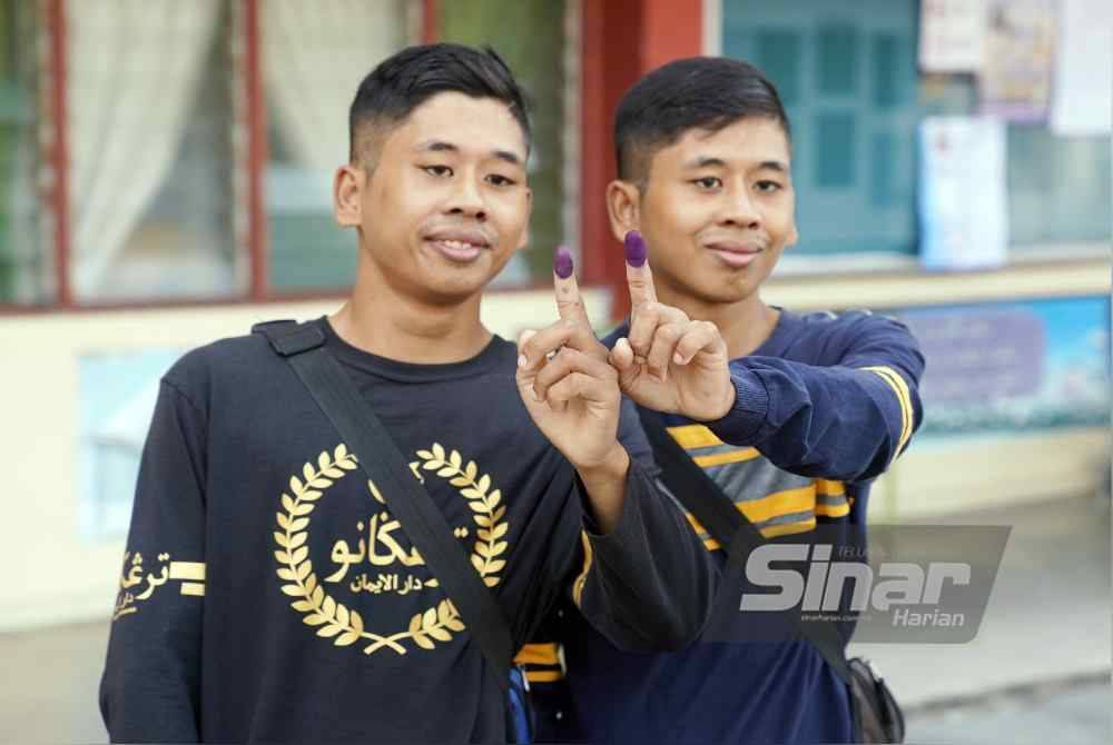 Muhammad Nazmi (kanan) dan Muhammad Nazri selesai mengundi di SK Bandar Baru Batang Kali sempena PRK Kuala Kubu Bharu pada Sabtu.