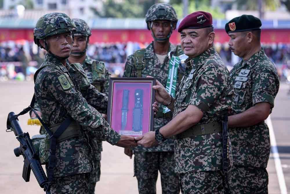 Muhammad Hafizuddeain (dua dari kanan) menyampaikan Anugerah Keseluruhan Terbaik Lelaki kepada perajurit muda, Ranfinddy Mail pada Perbarisan Tamat Latihan Perajurit Muda Lelaki Siri 199/23 di Padang Kawad Pusat Latihan Asas Tentera Darat (PUSASDA) hari ini. - Foto Bernama