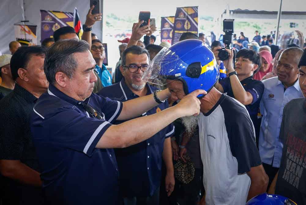 Menteri Pengangkutan Anthony Loke (kiri) menyerahkan helmet kepada orang ramai secara percuma pada majlis Ulang Tahun Hari ke-78 di Akademi Jabatan Pengangkutan Jalan (JPJ) Jalan Tiang Dua dekat Ayer Molek pada Sabtu. Foto Bernama