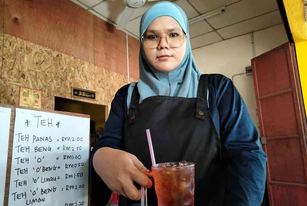 Siti Nurul Jannah menunjukkan teh O ais 50 sen yang kekal pada harga itu sejak tujuh tahun lalu