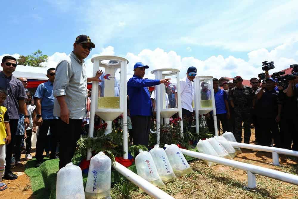 Saifuddin (kiri) menyempurnakan pelepasan anak ikan ke Sungai Perak sempena Majlis Peluncuran Kampung Angkat Madani KDN Kampung Beng di Jeti Pengkalan Pipit, Lenggong pada Ahad.