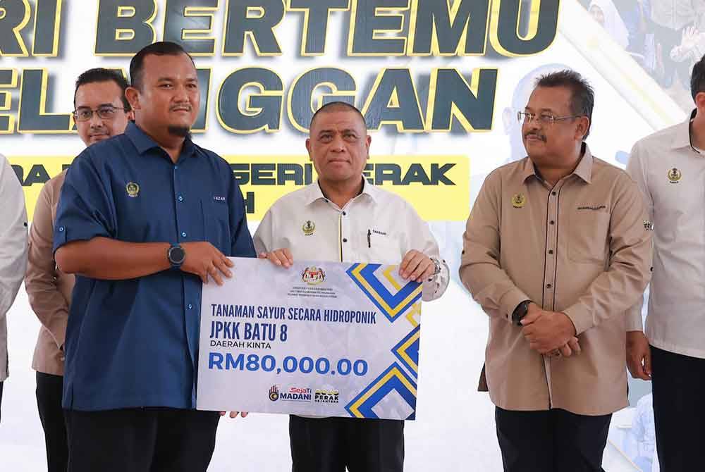 Saarani (dua dari kiri) menyampaikan dana yang diluluskan melalui Program Sejati Madani kepada salah satu komuniti ketika Program Mesra Hari Bertemu Pelanggan Kerajaan Negeri Perak 2024 Siri 3 di Dewan Merdeka Tapah pada Isnin.