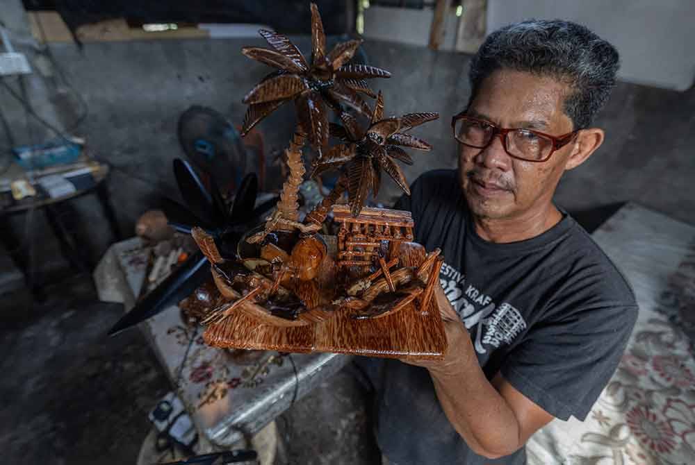 Mad Saril menunjukkan kraf tangan dari tempurung dan batang kelapa yang dihasilkan di bengkelnya di Kampung Sungai Betul baru-baru ini. Foto Bernama