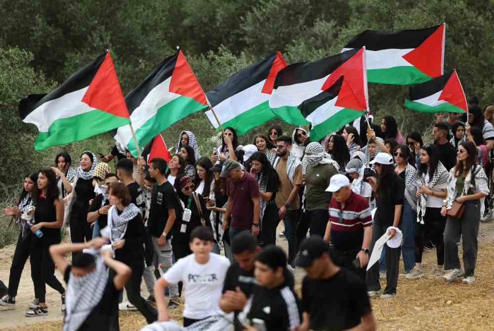 Orang ramai berarak dengan bendera kebangsaan Palestin semasa perhimpunan berhampiran bandar utara Israel Shefa Amr pada Selasa, menjelang perayaan Palestin sempena ulang tahun ke-76 Nakba. Foto AFP