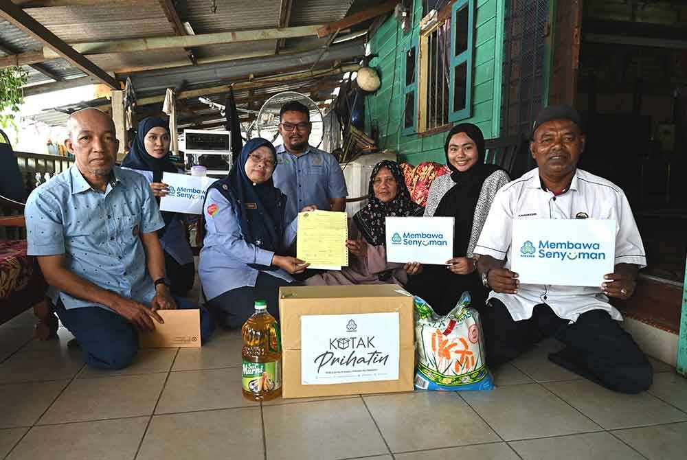 Farihah (dua dari kiri) menyampaikan surat pampasan kepada Noaini dan keluarga ketika ziarah prihatin Perkeso ke rumah mereka di Tanah Lot, Dungun pada Rabu.