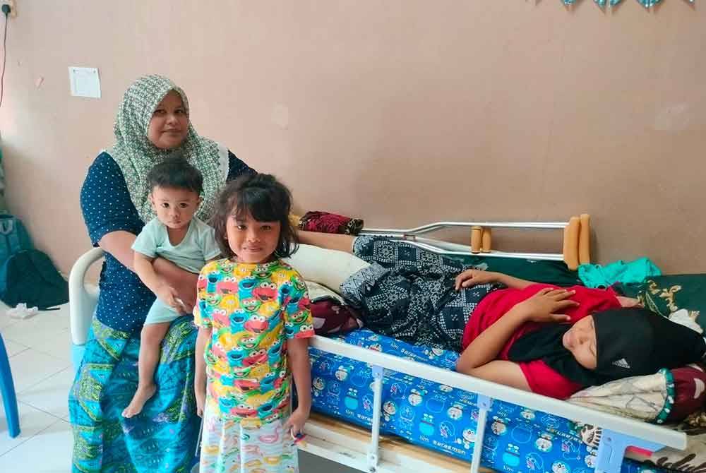 Lizawati (kiri) ketika menjaga anaknya NurulJannah Batrisia Mohd Nazsha,12, yang mengalami kecederaan ketika bersukan.