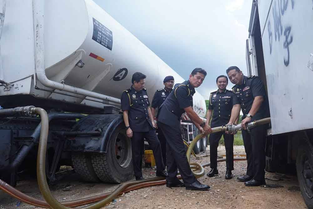 Mohd Zuhairi (dua dari kanan) melihat kaedah yang digunakan sindiket untuk melakukan pemindahan diesel di lokasi serbuan dekat Pulau Meranti, Puchong pada Rabu.