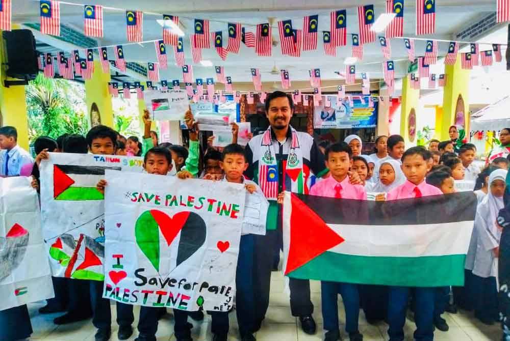 Mohd Tarmizi (tengah) bersama murid SK Kampung Kudung, Bekok, Labis, Segamat menunjukkan solidariti dan sokongan terhadap Palestin.