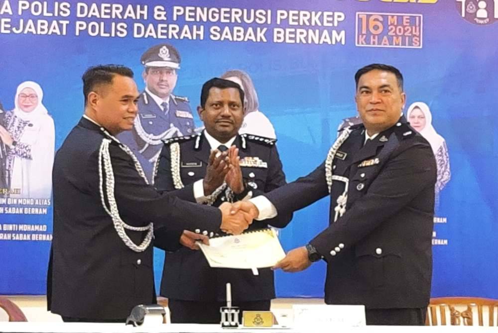 Khalid (kanan) dilantik sebagai pemangku Ketua Polis Daerah Sabak Bernam bagi menggantikan Agus Salim (kiri) sambil disaksikan Hussein (tengah) dalam majlis serah terima tugas di IPD Sabak Bernam, pada Khamis.