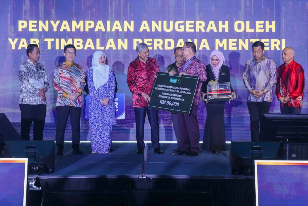 Ahmad Zahid menyampaikan Anugerah Tokoh Kepimpinan Pendidikan Kebangsaan 2024 kepada Datuk Suliaman @ Sulaiman Wak (empat dari kanan) pada Majlis Sambutan Hari Guru Peringkat Kebangsaan 2024 pada Khamis. Foto Bernama