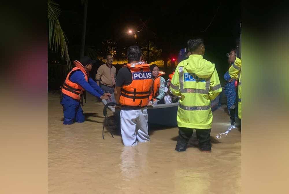 Anggota penyelamat membantu memindahkan mangsa banjir di Kampung Periang, Kuala Kangsar, malam tadi.