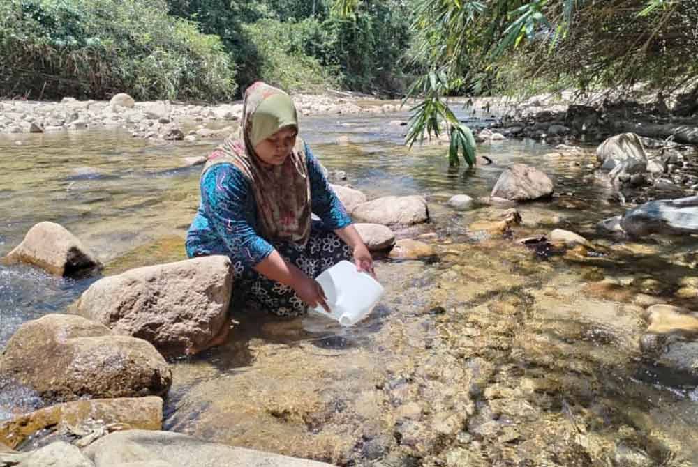 Che Siti Noraisyah mencuci beras di sungai selepas air perigi di rumahnya kering akibat musim kemarau yang melanda ketika ini.