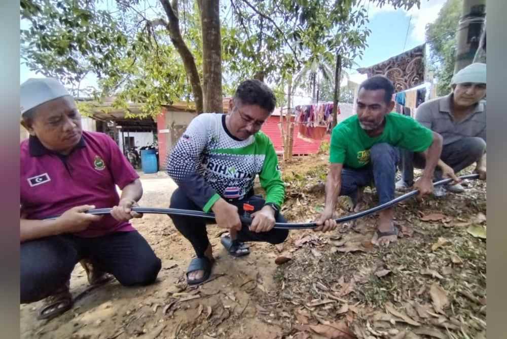 Mohd Husaimi (tengah) melihat pemasangan paip poli ketika meninjau kawasan yang mengalami gangguan bekalan air pada Jumaat.