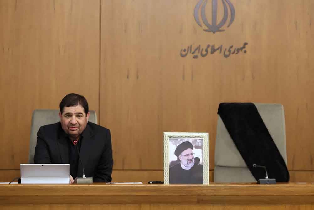 Mohammad Mokhber dengan kerusi Presiden Ebrahim Raisi (potret) di sebelahnya kosong, berucap pada kabinet negara itu di Tehran pada Ahad. Foto AFP/ HO/ Iranian Presidency