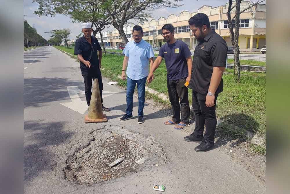 Harrison (dua dari kiri) bersama penduduk menunjukkan salah satu laluan berlubang yang meresahkan penduduk di Taman Alam Jaya dan Alam Perdana, Puncak Alam.