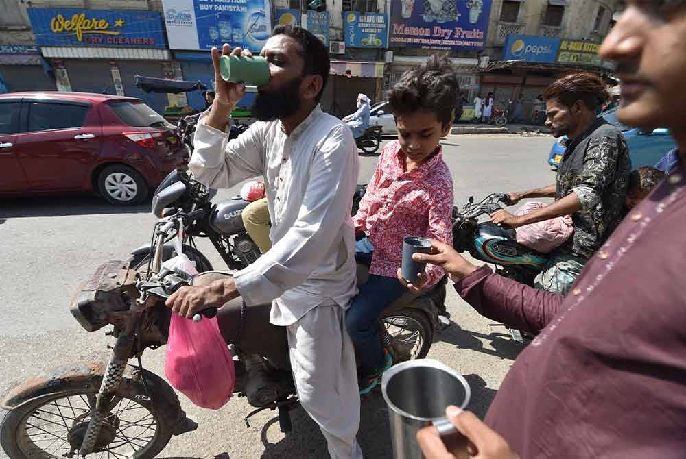 Sukarelawan mengedarkan air minuman kepada orang ramai di tepi jalan di Karachi, Pakistan. Jabatan Meteorologi Pakistan mengeluarkan amaran untuk gelombang panas yang berterusan di kebanyakan bahagian negara. Foto EPA