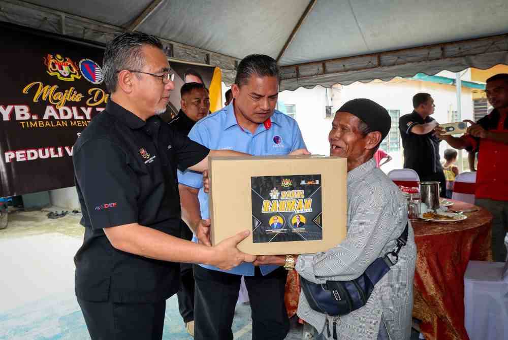 Adly (kiri) menyerahkan Bakul Rahmah kepada veteran ATM yang hadir Program Peduli Veteran ATM di Kampung Kuala Boh, Cameron Highlands pada Selasa. Foto Bernama