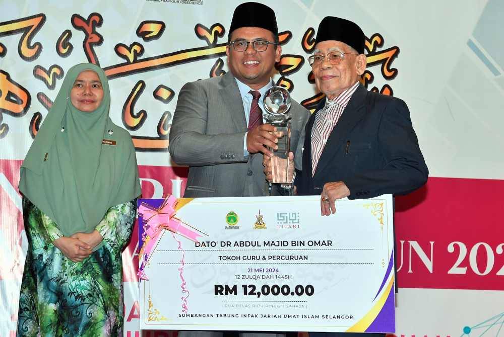 Amirudin (tengah) menyampaikan anugerah Tokoh Guru dan Perguruan kepada Datuk Dr Abdul Majid Omar pada sambutan Hari Guru JAIS di Dewan Jamuan Masjid Sultan Salahuddin Abdul Aziz Shah pada Selasa. Foto Bernama