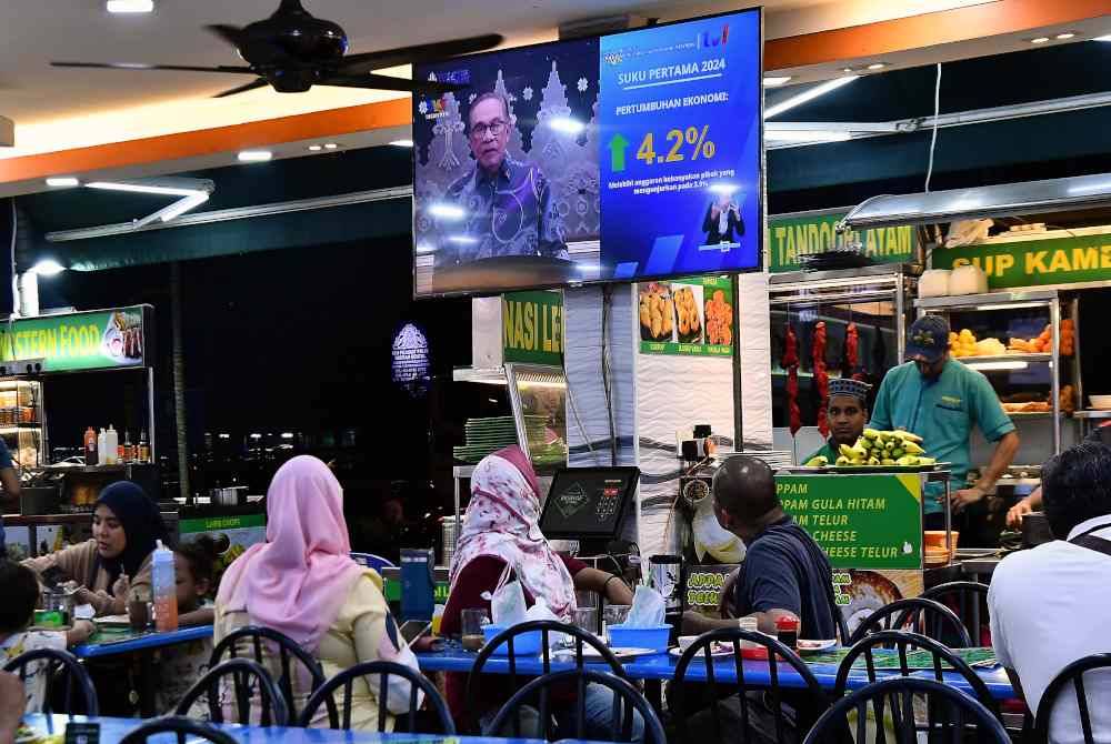 Orang ramai menyaksikan Perutusan Negara oleh Perdana Menteri yang disiarkan secara langsung melalui televisyen ketika tinjauan di sebuah restoran sekitar ibu kota malam ini. Foto Bernama