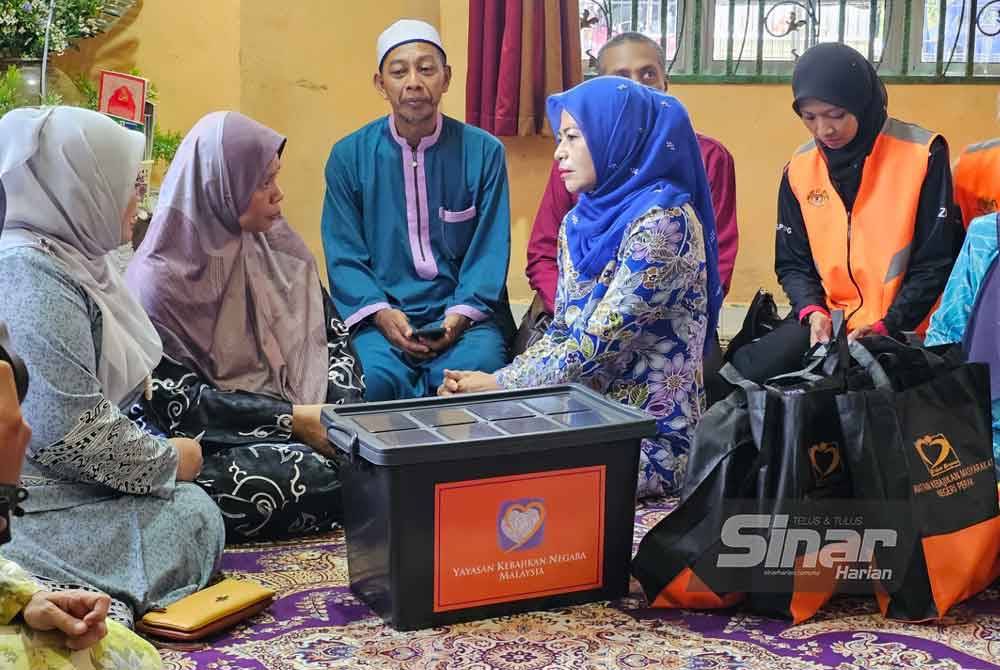 Noraini (tiga dari kanan) menyampaikan sumbangan Yayasan Kebajikan Negara kepada keluarga Allahyarham Konstabel Ahmad Azza Fahmi di Bidor pada Rabu.