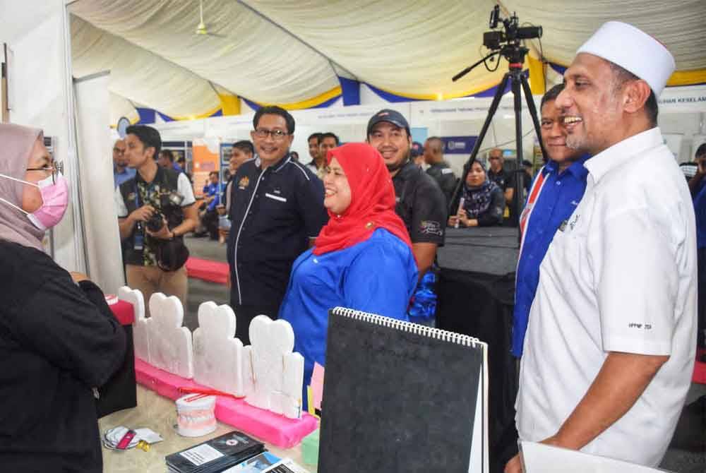 Rubiah (tengah) bersama Syed Ibrahim (kanan) menyantuni reruai yang mengambil bahagian PKD Mobile di Kuala Tahan, Jerantut, pada Jumaat.