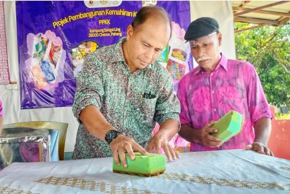 Juhari (tengah) mencuba blok batik menggunakan span bunga hasil Inovasi KK Kuala Terengganu.