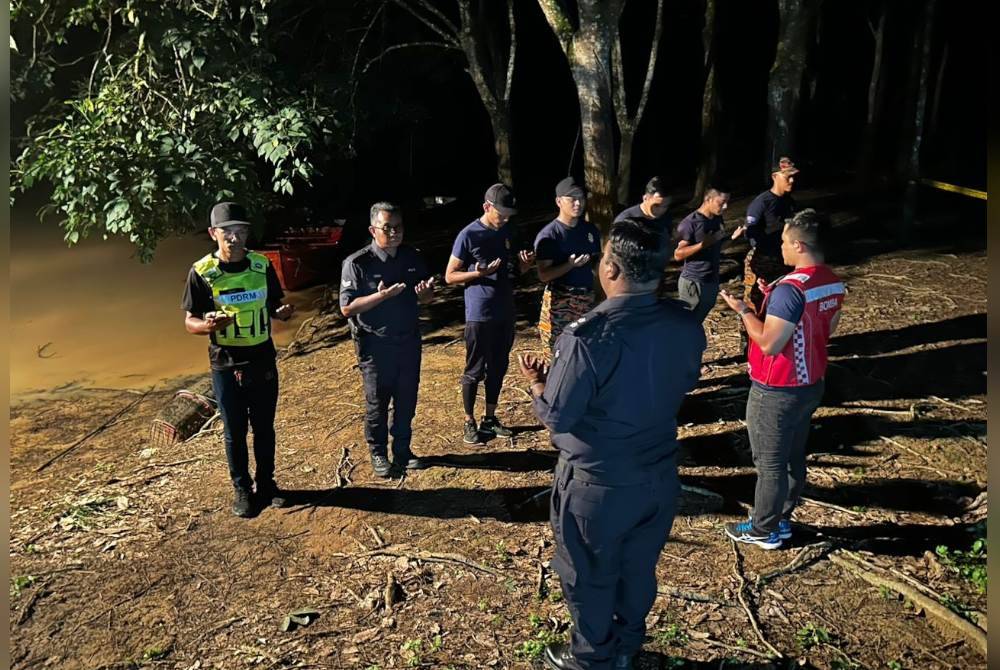 Anggota polis dan bomba membaca doa sebelum memulakan operasi SAR. Foto BBP Segamat