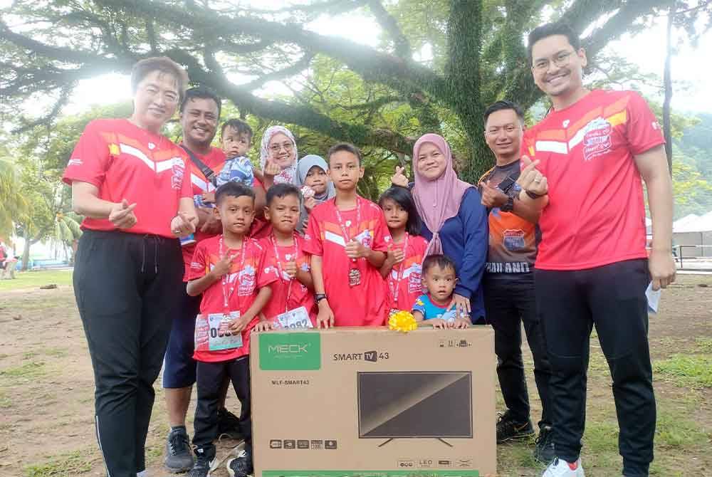 Mohd Haziq (depan, kiri) bersama kedua ibu bapa dan ahli keluarga yang mengambil bahagian dalam Pantai SP Fun Run menerima hadiah sebuah TV pintar. Turut serta Bee Chan (kiri) dan Mohammed Taufiq (kanan).