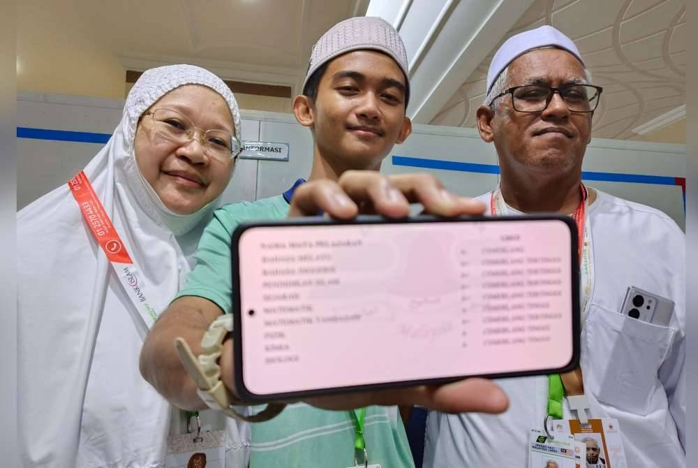 Muhammad Ameer bersama ibu bapanya menunjukkan keputusan cemerlang SPM diperolehnya, di sini, semalam.