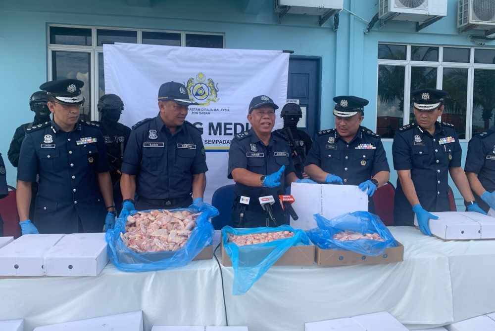 Mohd Nasir (tengah) menunjukkan daging ayam sejuk beku yang dirampas di Pelabuhan Sepanggar, Kota Kinabalu.