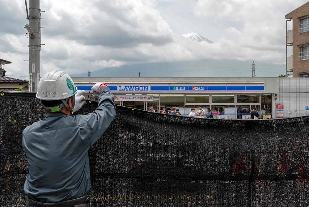 Seorang pekerja memasang penghadang pemandangan Gunung Fuji Jepun yang muncul dari belakang kedai serbaneka bagi mengelakkan pelancong yang berkelakuan buruk, di bandar Fujikawaguchiko, wilayah Yamanashi. Foto AFP