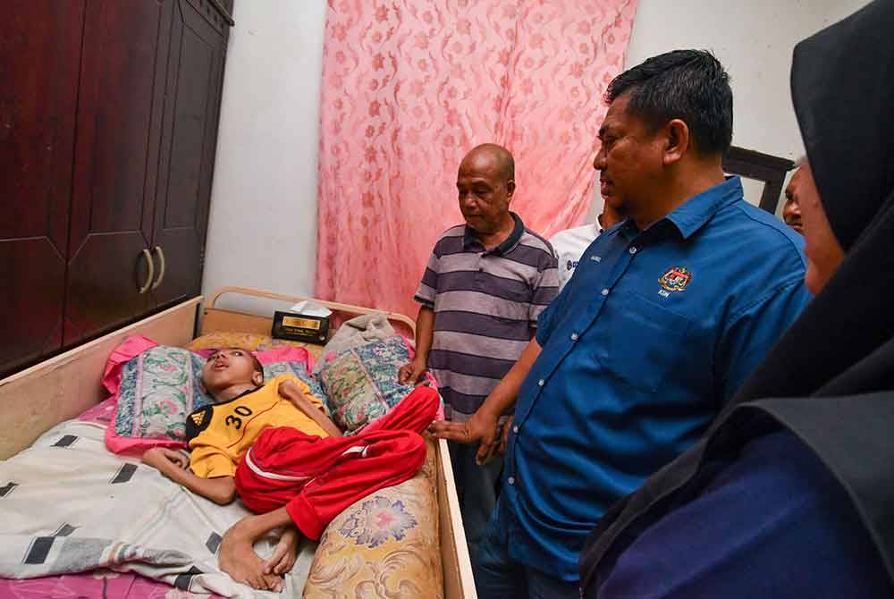 Badrul Hisham (tengah) melawat Afiq Aiman yang terlantar di kediamannya di Kampung Chenok pada Rabu.