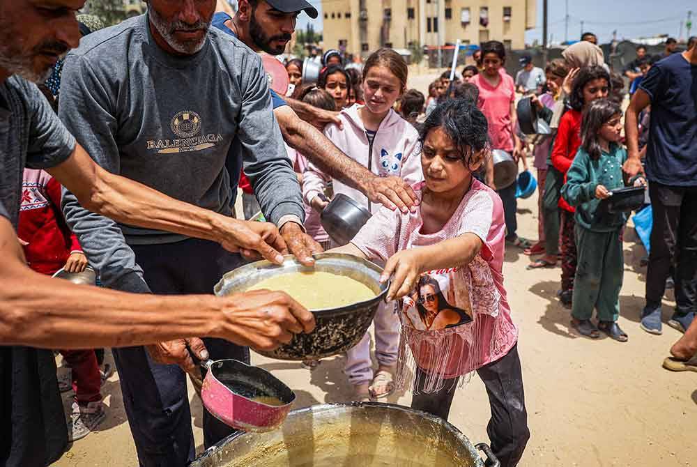 Sukarelawan mengagihkan makanan kepada kanak-kanak di Rafah.