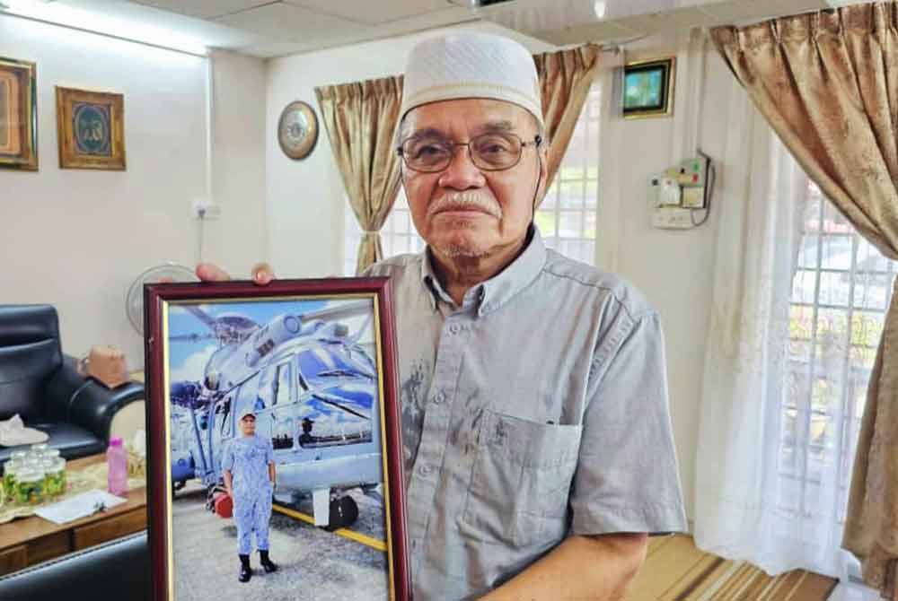 Mohd Termizi memegang potret Mohd Shahrizan yang telah berkhidmat dalam TLDM sejak 20 tahun lalu. Foto fail