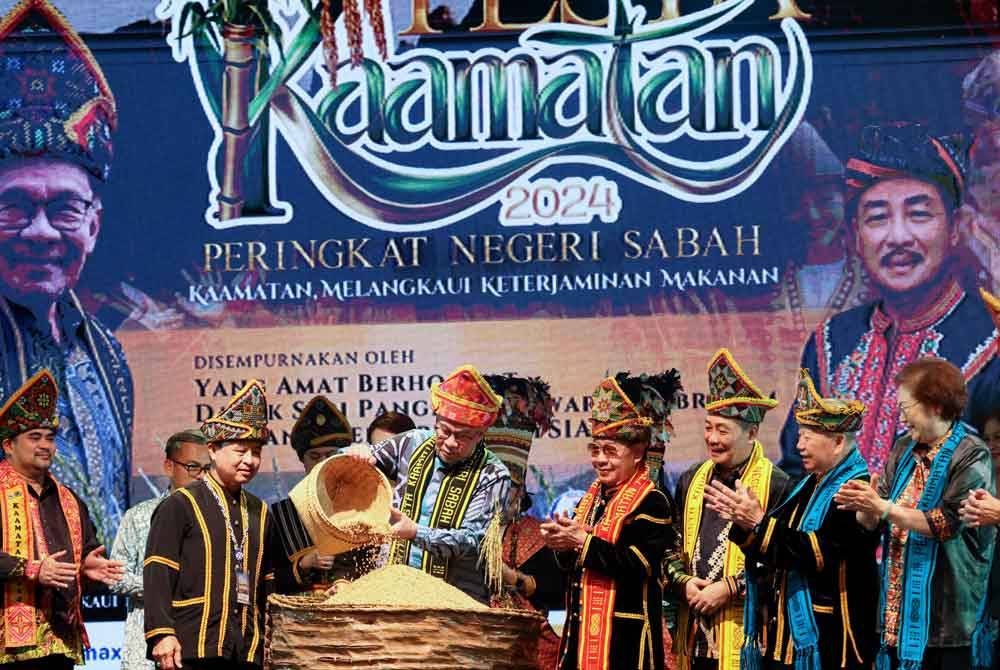 Anwar (tengah) menyimpan padi yang dituainya ke dalam bekas sebagai simbolik Majlis Penutup Sambutan Pesta Kaamatan Peringkat Negeri Sabah di Dewan Hongkod Koisaan, Persatuan Kebudayaan Kadazandusun (KDCA) di sini pada Jumaat. Foto Bernama